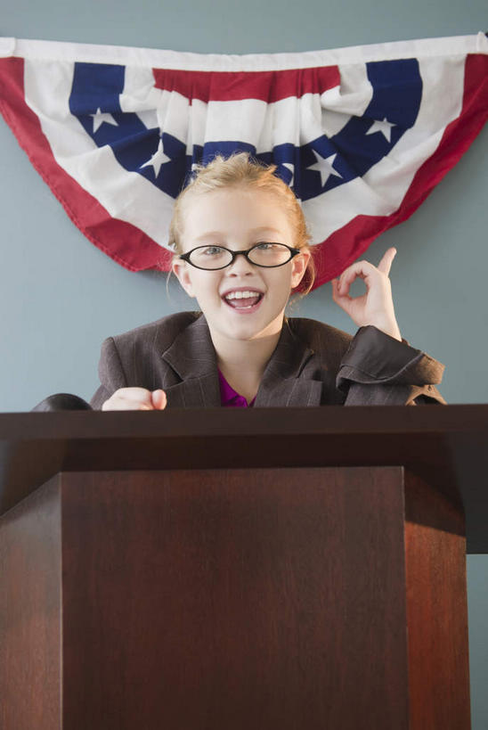 西方人,儿童,一个人,站,笑,微笑,露齿笑,竖图,室内,白天,正面,纯洁,欧洲,欧洲人,仅一个女性,仅一个人,一副,服装,眼镜,墙,注视,墙壁,墙面,小孩,衣服,讲台,观察,看,演讲,站着,仅一个小孩,可爱,童年,童趣,服饰,报告,观看,察看,演说,衣着,穿着,关注,演说台,宣传,近视眼镜,童真,演讲台,烂漫,无邪,衣饰,鼓动,讲演,天真,女孩,女人,女性,白种人,孩子,站立,半身,彩图,女生