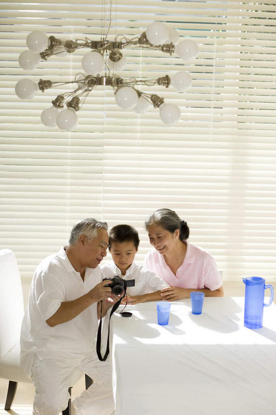 东方人,头发,三个人,祖母,祖父,站,坐,举,抱,笑,微笑,露齿笑,竖图,俯视,室内,白天,餐桌,窗户,落地窗,桌子,杯子,相机,椅子,照明,亚洲,握,阴影,服装,朦胧,模糊,光线,影子,百叶窗,木椅,灯光,拿,拿着,扭头,注视,休闲装,黄种人,吊灯,玻璃窗,灯,拍照,衣服,白色,数码相机,水杯,灯具,观察,看,托,站着,转头,休闲,休闲服,握着,摄影,服饰,奶奶,餐台,抱着,观看,祖孙,照亮,察看,搂着,照明设备,关注,外婆,外祖母,外公,外祖父,外孙,外孙子,鹤发,百页窗,亚洲人,孙子,茶杯,照相机,怀抱,举起,举手,举着,搂,搂抱,相抱,向上举,向上伸,向上托,拥抱,站立,坐着,半身,彩图,高角度拍摄,照相
