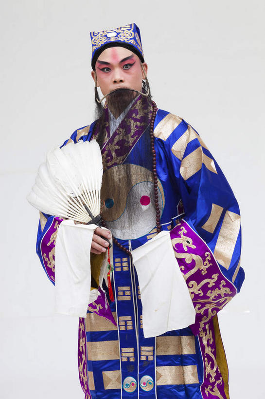 东方人,胡须,一个人,演员,站,竖图,室内,白天,正面,民族服装,化妆,帽子,亚洲,仅一个男性,仅一个人,仅一个中年男性,一把,表演,握,灰色背景,服装,扇子,清凉,拿,拿着,注视,黄种人,凉爽,文化,扮演,衣服,蓝色,彩妆,观察,看,站着,握着,摄影,服饰,影棚,观看,察看,演出,衣着,穿着,关注,中国文化,摄影棚,戏剧,表演服,演出服,京剧,戏曲,国粹,诸葛亮,皮黄,一顶,军事家,政治家,衣饰,羽毛扇,散文家,道具服,男人,男性,中年男性,亚洲人,胡子,络腮胡,站立,半身,彩图,影棚拍摄,传统服装,民俗服,拍摄,京剧服饰,羽扇,国剧,京戏,平剧,中国戏曲,忠武侯,武兴王,卧龙,伏龙,诸葛孔明,孔明,传统文化,舞台妆,京剧演员