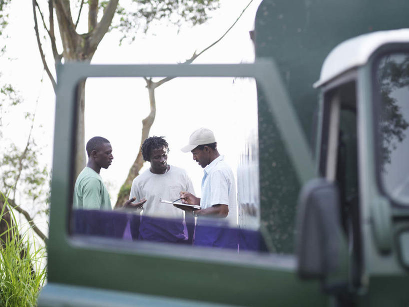 西方人,三个人,伙伴,朋友,站,笑,微笑,露齿笑,横图,室外,白天,正面,友谊,合作,团队,植物,卡车,微型货车,帽子,欧洲,非洲,黑人,欧洲人,握,服装,朦胧,模糊,笔,办公用品,集装箱,拿,拿着,注视,休闲装,运动帽,水笔,文具,树,树木,衣服,绿色,自然,学习用品,交通工具,观察,看,站着,休闲,休闲服,鸭舌帽,战略,握着,服饰,集装箱车,生长,成长,观看,货车,文具用品,察看,书写,关注,载具,记录板,货运车,记事板,联合,合谋,配合,协作,男人,男性,年轻男性,中年男性,非洲人,载重汽车,站立,半身,彩图