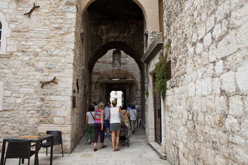 西方人,站,走,横图,室外,白天,旅游,度假,植物,桌面,桌子,标志建筑,地标,建筑,椅子,欧洲,克罗地亚,欧洲人,行人,游客,游人,阴影,服装,光线,木制,影子,墙,拱门,走道,走廊,过道,许多人,注视,休闲装,娱乐,建设,路人,旅客,墙壁,墙面,背面,衣服,绿色,阳光,自然,木制品,观察,看,站着,一群人,享受,休闲,休闲服,旅游胜地,放松,服饰,生长,成长,观看,察看,关注,首府,克罗地亚共和国,过客,斯普利特,戴克里先宫,斯普利特.达尔马提亚县,男人,男性,年轻男性,年轻女性,女人,女性,中年男性,中年女性,白种人,步行,散步,站立,走路,彩图,全身,斯普利特.达尔马提亚