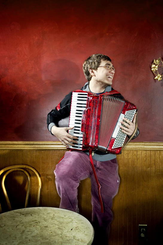 西方人,一个人,站,笑,微笑,露齿笑,竖图,室内,白天,正面,键盘,餐桌,房间,桌子,椅子,欧洲,欧洲人,仅一个男性,仅一个人,一副,握,阴影,服装,光线,眼镜,影子,木椅,墙,灯光,手风琴,拿,拿着,注视,休闲装,管风琴,墙壁,墙面,仅一个年轻男性,衣服,观察,回头,看,站着,转头,休闲,休闲服,弹,握着,服饰,餐台,观看,察看,键盘乐器,关注,近视眼镜,男人,男性,年轻男性,白种人,站立,半身,彩图