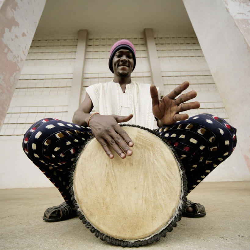 西方人,一个人,坐,横图,室外,白天,仰视,民族服装,帽子,欧洲,非洲,黑人,欧洲人,仅一个男性,仅一个人,敲打,鼓,音乐,仅一个年轻男性,拍,手鼓,棉帽,男人,男性,年轻男性,非洲人,坐着,半身,彩图,低角度拍摄,传统服装,民俗服