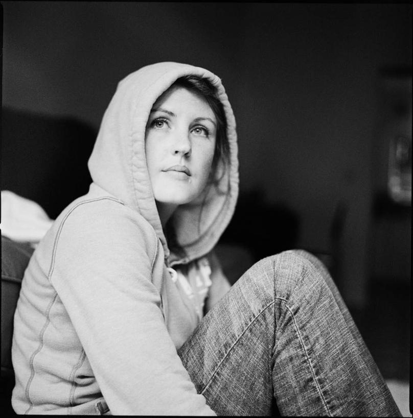 西方人,一个人,坐,竖图,室内,白天,侧面,欧洲,欧洲人,仅一个年轻女性,仅一个女性,仅一个人,阴影,服装,反射,影子,扭头,注视,休闲装,衣服,观察,看,转头,休闲,休闲服,服饰,观看,察看,关注,帽衫,年轻女性,女人,女性,白种人,坐着,半身,彩图