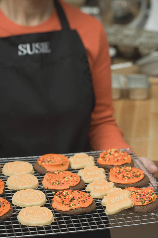 点心,西方人,一个人,站,竖图,室内,特写,白天,正面,欧洲,欧洲人,仅一个女性,仅一个人,一排,许多,握,服装,整齐,并列,并排,英文,标志,围裙,文字,字符,字母,食品,曲奇,很多,拿,拿着,标识,食物,排列,衣服,饼干,零食,站着,仅一个中年女性,橙色,握着,服饰,英文字母,衣着,穿着,队列,平行,曲奇饼,曲奇饼干,衣饰,女人,女性,中年女性,白种人,站立,半身,彩图