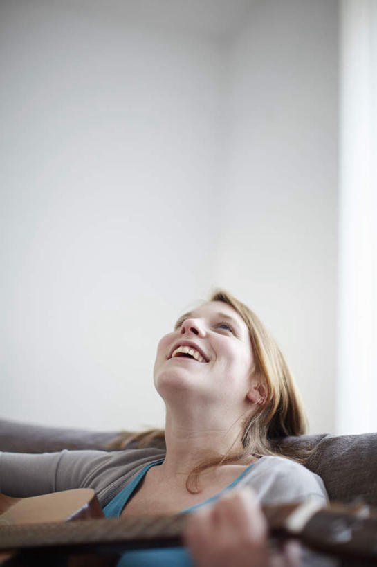 西方人,一个人,坐,抱,笑,微笑,露齿笑,竖图,室内,白天,正面,靠垫,沙发,欧洲,欧洲人,仅一个年轻女性,仅一个女性,仅一个人,服装,墙,棕色,吉他,靠枕,乐器,弦乐器,弹奏,二郎腿,演奏,注视,休闲装,墙壁,墙面,衣服,灰色,垫子,枕头,观察,看,休闲,休闲服,服饰,抱着,观看,察看,搂着,关注,弹拨弦鸣乐器,布艺沙发,年轻女性,女人,女性,白种人,长发,搂,抬头,仰头,坐着,半身,彩图,弹拨弦乐器