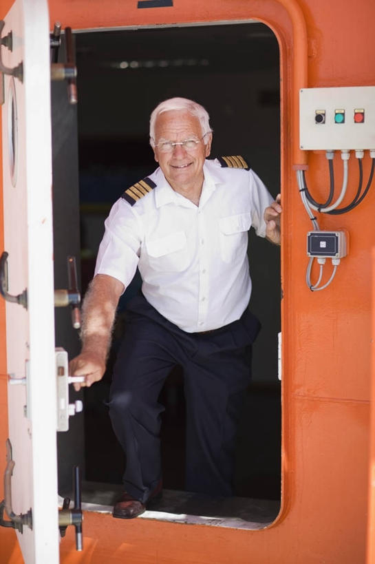 西方人,一个人,站,笑,微笑,露齿笑,竖图,室外,白天,正面,工作服,制服,门,欧洲,欧洲人,仅一个男性,仅一个人,握,阴影,光线,眼镜,影子,墙,注视,踩,墙壁,墙面,阳光,门框,踩着,打开,观察,看,站着,仅一个老年男性,橙色,握着,观看,老花镜,察看,开启,关注,工作制服,船长,远视眼镜,船主,老年男性,男人,男性,白种人,站立,彩图,全身,工作套服