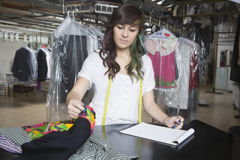 西方人,一个人,店员,商店,站,横图,室内,白天,正面,桌面,桌子,衣架,欧洲,欧洲人,仅一个年轻女性,仅一个女性,仅一个人,握,服装,朦胧,模糊,测量,木制,笔,皮尺,刻度,办公用品,记事本,拿,拿着,注视,休闲装,商铺,水笔,文具,衣服,本子,笔记本,尺,木制品,学习用品,低头,观察,看,站着,营业员,保养,休闲,休闲服,握着,保健,服饰,观看,测量工具,文具用品,尺子,减肥,察看,腰围尺,关注,瘦身,干洗店,量具,量仪,塑料卷尺,市肆,商号,销售人员,年轻女性,女人,女性,白种人,售货员,挂衣架,晾衣架,站立,半身,彩图,店铺