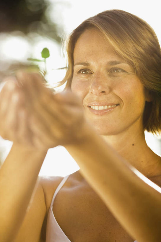 西方人,脸,头,脸颊,手,一个人,站,捧,笑,微笑,露齿笑,竖图,室外,特写,白天,正面,植物,吊带,欧洲,欧洲人,双手,仅一个女性,仅一个人,阴影,服装,朦胧,模糊,光线,影子,棕色,注视,吊带衫,幼苗,树,树木,衣服,粉色,绿色,阳光,自然,嫩芽,观察,看,站着,仅一个中年女性,手部,服饰,生长,成长,观看,察看,衣着,穿着,关注,一株,新苗,衣饰,女人,女性,中年女性,白种人,头部,脸部,脸蛋,面部,端,端着,捧着,手捧,站立,半身,彩图,短发