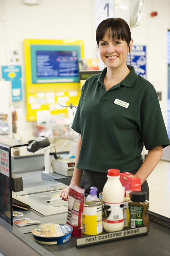 西方人,一个人,商店,站,笑,微笑,露齿笑,竖图,室内,白天,正面,工作服,制服,购物,消费,桌面,桌子,超市,欧洲,欧洲人,仅一个女性,仅一个人,许多,商品,注视,标识,吊牌,货物,胸牌,观察,看,站着,仅一个中年女性,pos机,金融,百货,收银台,观看,察看,徽章,关注,收银,收银机,身份,选购,贸易,百货公司,胸章,胸卡,血拼,编号牌,雕刻牌,工号牌,胸号牌,胸徽,员工牌,工作制服,女人,女性,中年女性,白种人,超级市场,大卖场,站立,半身,彩图,工作套服,购物商场,购物中心,商业中心