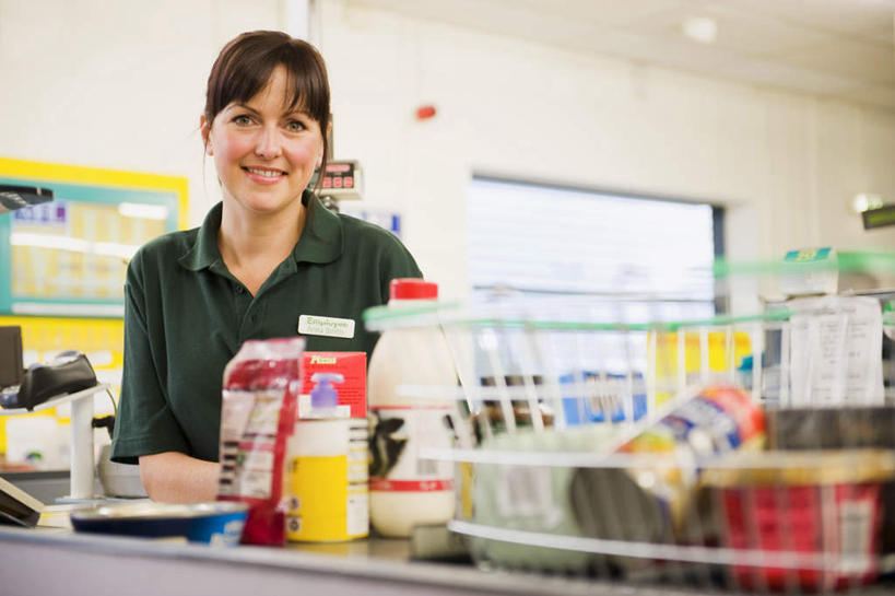 西方人,一个人,商店,站,笑,微笑,露齿笑,横图,室内,白天,正面,工作服,制服,购物,消费,桌面,桌子,超市,欧洲,欧洲人,仅一个女性,仅一个人,许多,商品,注视,标识,吊牌,货物,胸牌,观察,看,站着,仅一个中年女性,pos机,金融,百货,收银台,观看,察看,徽章,关注,收银,收银机,身份,选购,贸易,百货公司,胸章,胸卡,血拼,编号牌,雕刻牌,工号牌,胸号牌,胸徽,员工牌,工作制服,女人,女性,中年女性,白种人,超级市场,大卖场,站立,半身,彩图,工作套服,购物商场,购物中心,商业中心