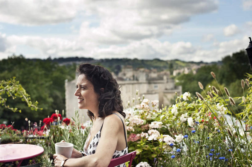 西方人,一个人,家,坐,笑,微笑,露齿笑,横图,室外,白天,侧面,草地,草坪,山,山脉,植物,桌面,桌子,杯子,椅子,吊带,欧洲,欧洲人,仅一个女性,仅一个人,握,阴影,服装,盛开,光线,木制,影子,陶瓷,房屋,墙,屋子,山峰,云,云朵,陶瓷制品,山峦,拿,花蕾,云彩,拿着,注视,吊带衫,楼房,墙壁,墙面,住宅,草,花,花瓣,花朵,鲜花,树,树木,一个,衣服,蓝色,绿色,白色,白云,蓝天,天空,阳光,自然,马克杯,木制品,水杯,群山,天,花苞,花蕊,观察,看,仅一个中年女性,握着,服饰,生长,晴朗,单个,成长,观看,察看,衣着,穿着,关注,衣饰,女人,女性,中年女性,白种人,晴空,坐着,半身,彩图,房子