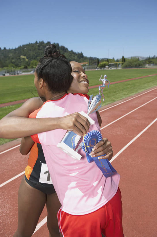 两个人,运动员,起跑线,站,抱,笑,微笑,露齿笑,竖图,室外,白天,侧面,锻炼,快乐,比赛,运动,竞争,非洲,黑人,塑胶,田径,跑道,竞技场,训练,拿,拿着,注视,娱乐,运动器械,观察,看,站着,休闲,健康,体育用品,抱着,观看,察看,搂着,体育运动,关注,奖牌,健身器材,体育,女人,女性,非洲人,搂,拥抱,站立,半身,彩图,健身,奖杯