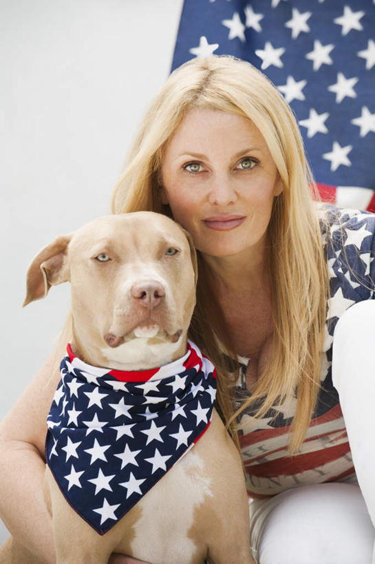 蝶泳,西方人,一个人,坐,抱,笑,微笑,露齿笑,室外,白天,正面,宠物,狗,旗帜,国旗,欧洲,欧洲人,仅一个女性,仅一个人,阴影,服装,反射,影子,猎犬,猎兔犬,注视,休闲装,星条旗,一只,衣服,动物,观察,看,仅一个中年女性,休闲,休闲服,可爱,美国国旗,服饰,抱着,观看,察看,搂着,关注,忠诚,女人,女性,中年女性,白种人,旗,犬,搂,搂抱,坐着,半身,彩图,美利坚合众国国旗,法老王猎犬,科博特菲勒犬,投票