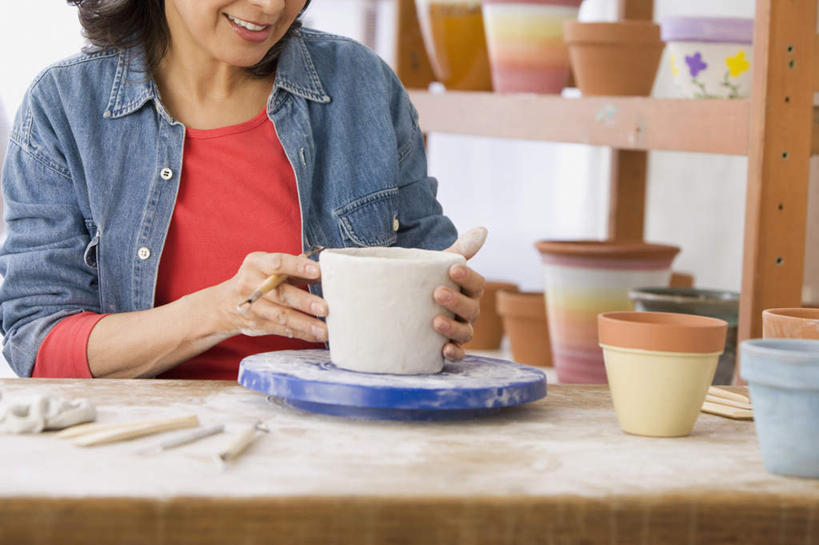 西方人,一个人,雕刻家,坐,笑,微笑,露齿笑,横图,室内,白天,正面,桌面,桌子,雕塑,欧洲,欧洲人,仅一个女性,仅一个人,握,服装,艺术,装饰,木制,雕刻,雕像,手工艺品,拿,置物架,拿着,休闲装,文化,架子,衣服,木制品,工艺品,仅一个中年女性,休闲,休闲服,握着,服饰,纪念,美术,粘土,高雅,主题,陈列架,陈列,手工艺,功能,美学,自信心,品位,搁架,女人,女性,中年女性,白种人,雕塑家,坐着,半身,彩图