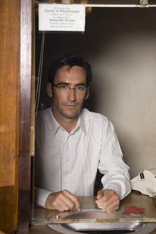 西方人,一个人,店员,坐,笑,微笑,竖图,室内,白天,正面,电影院,剧院,欧洲,欧洲人,仅一个男性,仅一个人,仅一个中年男性,服装,英文,标志,文字,纸,字符,字母,窗口,注视,休闲装,标识,衣服,观察,看,营业员,休闲,休闲服,服饰,观看,英文字母,售票,察看,关注,售票窗,售票窗口,销售人员,男人,男性,中年男性,白种人,售货员,坐着,半身,彩图,剧场