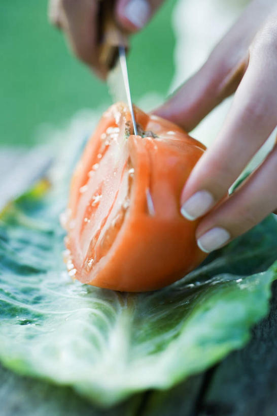 手,竖图,俯视,室外,白天,餐桌,桌子,西红柿,水果,叶子,切开,食品,分开,毛巾,刀,切,手部,餐台,水果刀,小刀,菜刀,剖面,切面,叶,叶片,番茄,半身,彩图,高角度拍摄