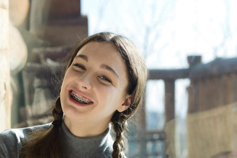 西方人,脸,头,脸颊,一个人,家,站,笑,微笑,露齿笑,横图,室外,特写,白天,正面,植物,欧洲,欧洲人,仅一个年轻女性,仅一个女性,仅一个人,朦胧,模糊,房屋,屋子,枯树,楼房,肩膀,住宅,树,树干,树木,绿色,自然,模型,站着,生长,成长,模具,矫正,牙科,牙套,牙箍,校正,校准,牙饰,年轻女性,女人,女性,白种人,头部,脸部,脸蛋,面部,站立,半身,彩图,房子