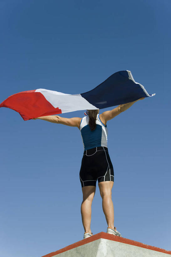 西方人,一个人,运动员,站,伸展双臂,竖图,室外,白天,仰视,运动服,旗帜,国旗,欧洲,欧洲人,仅一个女性,仅一个人,阴影,服装,光线,影子,衣服,蓝色,蓝天,天空,阳光,天,站着,仅一个中年女性,服饰,晴朗,颁奖台,衣着,穿着,法国国旗,万里无云,衣饰,女人,女性,中年女性,白种人,旗,晴空,晴空万里,体育运动员,运动选手,敞开双臂,伸开双臂,展开双肩,站立,张开手臂,张开双臂,彩图,低角度拍摄,全身,三色旗,运动装
