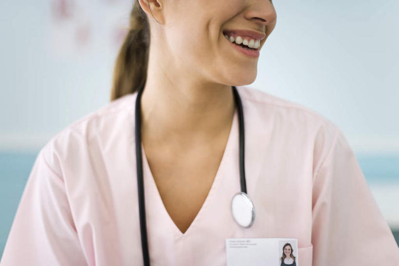 西方人,脸,头,脸颊,一个人,医生,医院,站,笑,微笑,露齿笑,横图,室内,特写,白天,正面,工作服,制服,名片,欧洲,欧洲人,仅一个年轻女性,仅一个女性,仅一个人,粉色,听诊器,站着,医护人员,医疗人员,名牌,医疗设备,医疗机构,工作制服,年轻女性,女人,女性,白种人,头部,脸部,脸蛋,面部,大夫,站立,半身,彩图,工作套服,病院,诊所