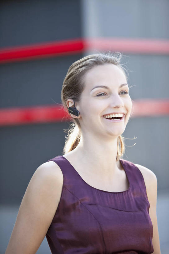 西方人,一个人,站,笑,微笑,露齿笑,竖图,室外,白天,正面,通讯,欧洲,欧洲人,仅一个年轻女性,仅一个女性,仅一个人,条纹,朦胧,模糊,信息,墙,注视,墙壁,墙面,红色,黑色,耳机,耳麦,话筒,观察,看,站着,通信,观看,协调,察看,麦克风,关注,扩音器,蓝牙,蓝牙耳机,传声器,微音器,年轻女性,女人,女性,白种人,站立,半身,彩图