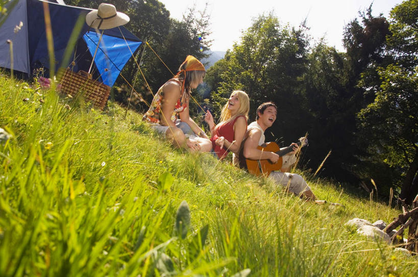 西方人,三个人,伙伴,朋友,坐,笑,微笑,露齿笑,横图,室外,白天,侧面,旅游,度假,友谊,草地,草坪,植物,欧洲,欧洲人,阴影,服装,光线,影子,帐篷,吉他,乐器,弦乐器,注视,娱乐,草,树,树木,衣服,绿色,阳光,自然,观察,看,享受,休闲,放松,服饰,生长,成长,观看,察看,篝火,衣着,穿着,关注,弹拨弦鸣乐器,露营,野营,户外运动,衣饰,友情,男人,男性,年轻男性,年轻女性,女人,女性,白种人,坐着,彩图,全身,弹拨弦乐器