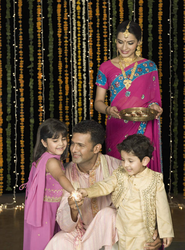 儿童,痣,四个人,家庭,夫妻,母亲,父亲,女儿,儿子,站,蹲,捧,笑,微笑,露齿笑,竖图,室内,白天,正面,民族服装,爱情,纯洁,项链,照明,亚洲,灯光,浪漫,拿,拿着,注视,灯,装饰品,小孩,耳环,饰品,手链,首饰,灯具,观察,看,祈福,站着,温暖,温馨,父女,父子,母女,母子,一家人,恩爱,父爱,可爱,母爱,童年,童趣,恋人,服饰,手镯,观看,飘逸,烟火棒,照亮,戴着,和睦,察看,庄重,照明设备,关注,油灯,追求,镯子,童真,烂漫,无邪,纱丽,吉祥痣,朱砂痣,雅致,避邪,耳饰,消灾,纱丽服,清婉,妍丽,迪勒格,天真,男孩,男人,男性,年轻男性,年轻女性,女孩,女人,女性,亚洲人,印度人,孩子,年轻人,夫妇,情侣,端,端着,蹲着,捧着,手捧,站立,半身,彩图,传统服装,民俗服,伴侣,融洽,男生,女生,奢华