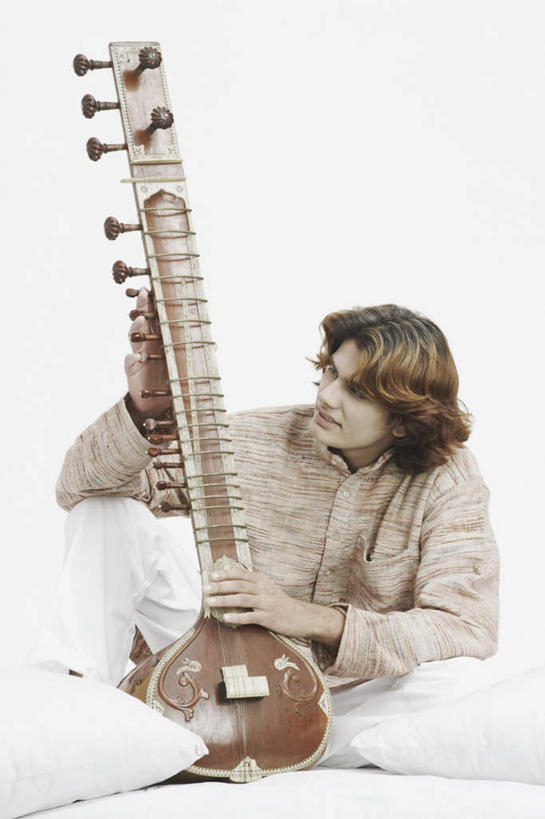 一个人,坐,盘腿,竖图,室内,白天,白色背景,正面,民族服装,靠垫,亚洲,仅一个男性,仅一个人,握,服装,靠枕,乐器,弦乐器,拿,拿着,注视,仅一个年轻男性,衣服,抱枕,枕头,观察,看,握着,摄影,服饰,影棚,观看,察看,衣着,穿着,关注,弓拉弦乐器,弓拉弦鸣乐器,西塔尔,西塔琴,衣饰,锡塔尔琴,男人,男性,年轻男性,亚洲人,印度人,盘腿而坐,盘膝,盘着腿的,盘着腿坐,双腿交叉,坐着,彩图,全身,影棚拍摄,传统服装,民俗服,拍摄