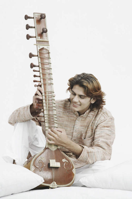 一个人,坐,盘腿,竖图,室内,白天,白色背景,正面,民族服装,靠垫,亚洲,仅一个男性,仅一个人,握,服装,靠枕,乐器,弦乐器,拿,拿着,注视,仅一个年轻男性,衣服,抱枕,枕头,观察,看,握着,摄影,服饰,影棚,观看,察看,衣着,穿着,关注,弓拉弦乐器,弓拉弦鸣乐器,西塔尔,西塔琴,衣饰,锡塔尔琴,男人,男性,年轻男性,亚洲人,印度人,盘腿而坐,盘膝,盘着腿的,盘着腿坐,双腿交叉,坐着,彩图,全身,影棚拍摄,传统服装,民俗服,拍摄