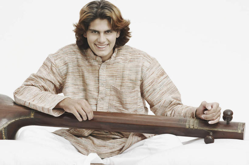 一个人,坐,盘腿,横图,室内,白天,白色背景,正面,民族服装,靠垫,亚洲,仅一个男性,仅一个人,握,服装,靠枕,乐器,弦乐器,拿,拿着,注视,仅一个年轻男性,衣服,抱枕,枕头,观察,看,握着,摄影,服饰,影棚,观看,察看,衣着,穿着,关注,弓拉弦乐器,弓拉弦鸣乐器,西塔尔,西塔琴,衣饰,锡塔尔琴,男人,男性,年轻男性,亚洲人,印度人,盘腿而坐,盘膝,盘着腿的,盘着腿坐,双腿交叉,坐着,彩图,全身,影棚拍摄,传统服装,民俗服,拍摄