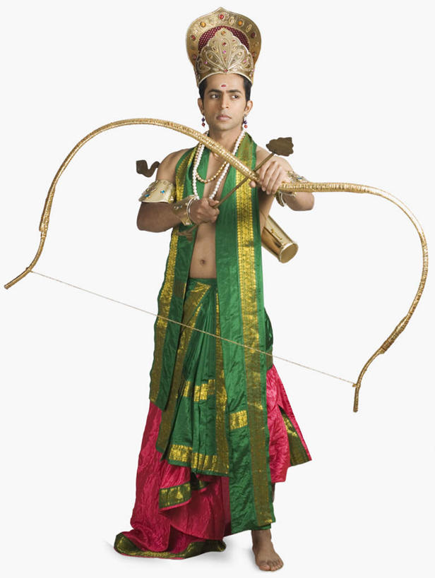 一个人,站,竖图,室内,白天,白色背景,正面,民族服装,帽子,项链,亚洲,仅一个男性,仅一个人,握,服装,弓,弓箭,拿,拿着,注视,装饰品,仅一个年轻男性,衣服,耳环,饰品,首饰,观察,看,站着,握着,摄影,服饰,影棚,观看,合金,黄铜,豆蔻,察看,衣着,穿着,关注,表演服,演出服,印度教,耳饰,衣饰,道具服,男人,男性,年轻男性,亚洲人,印度人,站立,彩图,全身,影棚拍摄,传统服装,民俗服,拍摄,传统文化