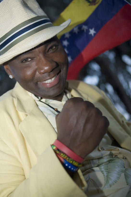 西方人,一个人,站,笑,微笑,露齿笑,竖图,室外,白天,正面,旗帜,国旗,帽子,项链,欧洲,非洲,黑人,欧洲人,仅一个男性,仅一个人,仅一个中年男性,握,服装,注视,休闲装,鼓励,装饰品,衣服,耳环,饰品,手链,首饰,遮阳帽,观察,加油,看,手势,握拳,站着,休闲,休闲服,打气,握着,服饰,手镯,观看,察看,关注,鼓舞,镯子,耳饰,男人,男性,中年男性,非洲人,旗,站立,半身,彩图