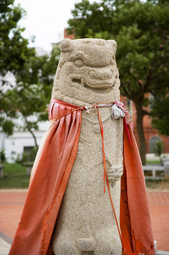 无人,竖图,室外,白天,正面,旅游,度假,植物,哺乳动物,野生动物,狮子,雕塑,台湾,中国,亚洲,艺术,装饰,雕刻,雕像,娱乐,石雕,树,树木,红色,绿色,自然,动物,工艺品,享受,休闲,放松,生长,成长,纪念,美术,主题,凶猛,斗篷,陈列,东亚,港澳台,中华人民共和国,功能,美学,台湾省,大氅,残暴,凶残,半身,彩图,金门,金门县,风狮,风狮爷,石狮公,石狮爷,台