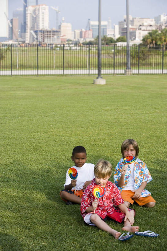 西方人,儿童,三个人,伙伴,朋友,高楼大厦,栏杆,坐,吃,盘腿,竖图,室外,白天,正面,友谊,纯洁,办公楼,草地,草坪,植物,大厦,建筑,摩天大楼,写字楼,欧洲,非洲,黑人,欧洲人,握,阴影,服装,光线,棒棒糖,影子,围栏,食品,糖,糖果,甜点,甜品,拿,拿着,注视,休闲装,护栏,草,食物,小孩,衣服,蓝色,绿色,蓝天,天空,阳光,楼宇,甜食,天,观察,看,休闲,休闲服,商务楼,可爱,童年,童趣,握着,服饰,晴朗,观看,察看,关注,童真,烂漫,无邪,波板糖,万里无云,天真,友情,男孩,男人,男性,白种人,非洲人,晴空,晴空万里,嚼,盘腿而坐,盘膝,盘着腿的,盘着腿坐,食,双腿交叉,坐着,彩图,全身,大楼,高层建筑,高楼,摩天楼,男生