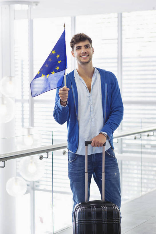 西方人,一个人,机场,栏杆,站,笑,微笑,露齿笑,竖图,室内,白天,正面,窗户,落地窗,飞机场,旗帜,欧洲,欧洲人,仅一个男性,仅一个人,握,阴影,服装,环绕,围绕,反射,圆形,拉杆箱,旅行箱,图形,影子,圆,星星,围栏,几何,拿,环抱,拿着,注视,休闲装,旗子,护栏,玻璃窗,仅一个年轻男性,衣服,黄色,蓝色,行李箱,箱子,观察,看,站着,休闲,星形,休闲服,握着,服饰,观看,出差,察看,关注,数学,五角形,欧盟旗帜,旌旗,旗号,萦绕,男人,男性,年轻男性,白种人,航空站,空港,五角星,站立,半身,彩图,旅行,几何图形,平面图形