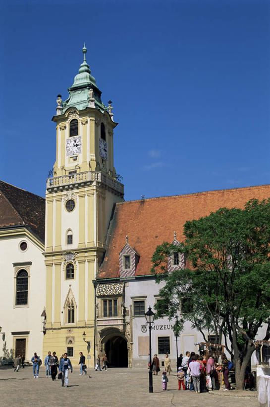 西方人,儿童,无人,高楼大厦,站,走,竖图,室外,白天,正面,旅游,度假,办公楼,植物,窗户,门,标志建筑,大厦,地标,建筑,路灯,摩天大楼,写字楼,指示牌,照明,欧洲,斯洛伐克,欧洲人,阴影,服装,时间,光线,英文,标志,时钟,文字,影子,字符,字母,墙,屋顶,钟楼,灯光,首都,许多人,计时,顶棚,注视,休闲装,娱乐,标识,建设,玻璃窗,墙壁,墙面,灯,树,树木,小孩,衣服,蓝色,绿色,蓝天,天空,阳光,自然,门框,钟表,楼宇,天,观察,看,站着,一群人,享受,休闲,休闲服,表,旅游胜地,商务楼,放松,服饰,生长,晴朗,成长,观看,英文字母,照亮,察看,照明设备,关注,市政厅,中欧,万里无云,首府,塔钟,布拉迪斯拉发,斯洛伐克共和国,西斯洛伐克州,男孩,男人,男性,女孩,女人,女性,中年男性,中年女性,白种人,孩子,钟,晴空,晴空万里,步行,散步,站立,走路,彩图,大楼,高层建筑,高楼,摩天楼,男生,女生