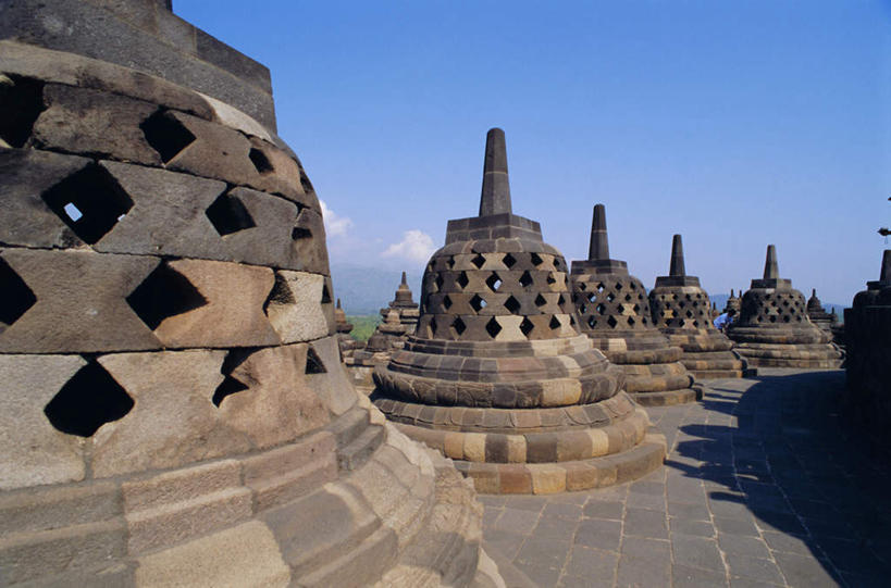 无人,寺庙,横图,室外,白天,正面,旅游,度假,植物,标志建筑,地标,建筑,雕塑,印度尼西亚,印尼,亚洲,阴影,节日,艺术,装饰,光线,雕刻,雕像,影子,墙,屋顶,云,云朵,燃烧,云彩,顶棚,文化,娱乐,建设,墙壁,墙面,树,树木,蓝色,绿色,白云,蓝天,天空,阳光,自然,香火,工艺品,庙宇,天,祈祷,享受,休闲,健康,旅游胜地,放松,许愿,宗教,东南亚,信仰,生长,晴朗,成长,纪念,祈求,美术,主题,陈列,印度尼西亚共和国,功能,美学,婆罗浮屠塔,婆罗浮屠,爪哇,爪哇岛,婆罗浮屠寺庙群,千佛坛,日惹,平安,晴空,彩图,庙,寺