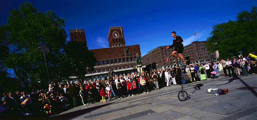 西方人,站,横图,室外,白天,正面,旅游,度假,植物,标志建筑,道路,地标,建筑,路,公路,挪威,欧洲,欧洲人,一辆,表演,阴影,光线,影子,建筑群,交通,许多人,注视,娱乐,建设,车,树,树木,扮演,蓝色,绿色,蓝天,天空,阳光,自然,手推车,交通工具,天,观察,看,站着,一群人,享受,休闲,放松,独轮车,生长,晴朗,成长,观看,察看,演出,斯堪的纳维亚,关注,载具,北欧,斯堪的纳维亚半岛,万里无云,挪威王国,男人,男性,年轻男性,年轻女性,女人,女性,白种人,晴空,晴空万里,马路,站立,半身,彩图