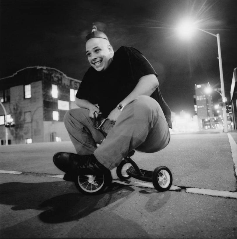 西方人,一个人,家,坐,笑,微笑,露齿笑,竖图,黑白,室外,夜晚,正面,道路,路,路灯,公路,照明,欧洲,欧洲人,仅一个男性,仅一个人,仅一个中年男性,服装,时间,时钟,手表,房屋,屋子,灯光,交通,计时,休闲装,楼房,住宅,车,灯,衣服,钟表,休闲,休闲服,表,服饰,腕表,照亮,照明设备,载具,儿童车,男人,男性,中年男性,白种人,钟,马路,坐着,全身,房子