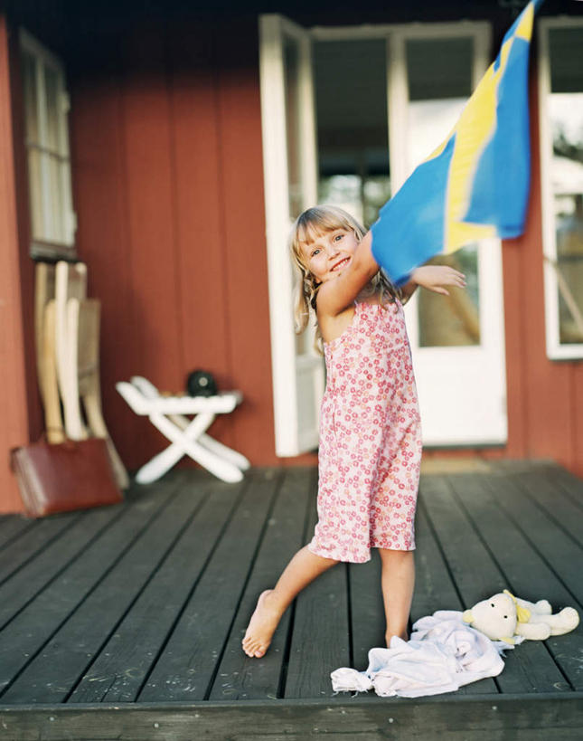 西方人,儿童,一个人,家,站,举,笑,交叉,微笑,露齿笑,竖图,室外,白天,正面,纯洁,窗户,旗帜,国旗,欧洲,欧洲人,仅一个女性,仅一个人,握,阴影,条纹,光线,影子,房屋,屋子,公寓,拿,拿着,注视,洋房,楼房,玻璃窗,住宅,小孩,黄色,蓝色,阳光,观察,看,托,站着,仅一个小孩,可爱,童年,童趣,握着,观看,察看,挥动,挥舞,关注,童真,烂漫,无邪,相交,交集,天真,女孩,女人,女性,白种人,孩子,旗,举起,举手,举着,向上举,向上伸,向上托,站立,彩图,全身,房子,瑞典国旗,女生