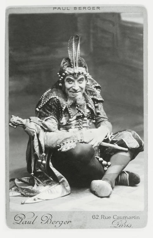 成年人,老年人,胡须,一个人,坐,竖图,黑白,室内,正面,神秘,仅一个男性,仅一个人,仅一个中年男性,表演,拿着,表演者,扮演,彩妆,幻想,人体,摄影,英文字母,幽默,创造力,演出,肖像,演出服,男人,男性,中年男性,胡子,络腮胡,盘着腿坐,传统服装,舞台妆