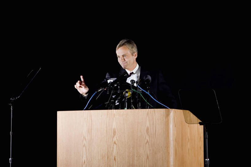 西方人,一个人,商务人士,商务男性,舞台,站,笑,微笑,露齿笑,横图,室内,白天,正面,衬衫,西装,欧洲,欧洲人,仅一个男性,仅一个人,仅一个中年男性,指,阴影,套装,正装,光线,影子,领带,注视,职业装,方向,话筒,发言,观察,看,手势,演讲,站着,观看,察看,麦克风,指向,食指,关注,扩音器,政治,传声器,工薪阶层,竞选,微音器,记者会,记者招待会,男人,男性,中年男性,白种人,白领,上班族,表演台,讲话,站立,半身,彩图,衬衣,演说家