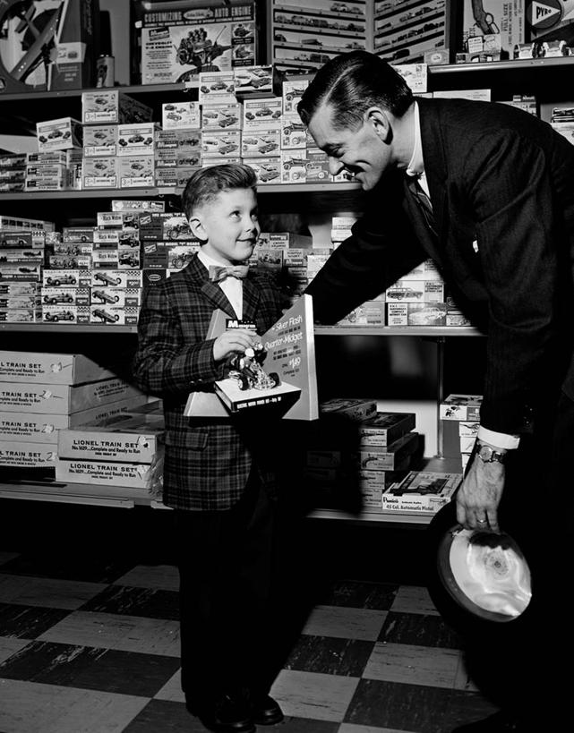 西方人,儿童,成年人,中年人,两个人,家庭,父亲,儿子,商店,站,微笑,竖图,黑白,室内,白天,购物,纯洁,复古,合作,消费,玩具,欧洲,纽约,美国,欧洲人,弯腰,套装,正装,领结,商品,古典,拿着,顾客,架子,球,小孩,球体,温暖,温馨,一家人,可爱,零售,童年,童趣,服务,摄影,英文字母,和睦,童真,玩具店,烂漫,无邪,天真,男孩,男性,中年男性,白种人,孩子,售货员,休闲活动,融洽