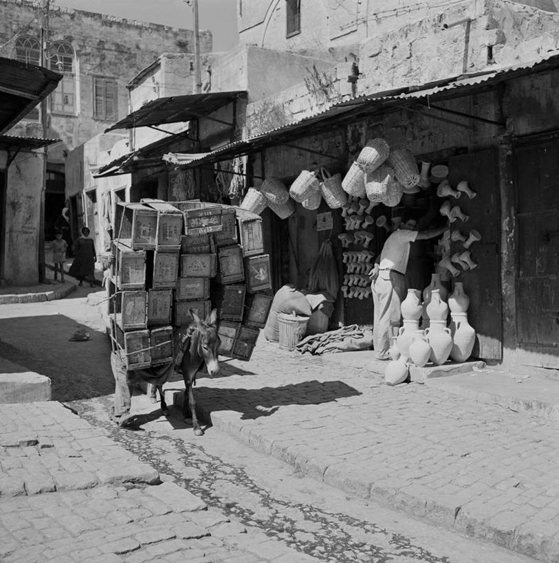 成年人,一个人,站,竖图,方图,黑白,室外,白天,建筑,街道,以色列,美国,仅一个男性,堆叠,篮子,古城,货摊,盒子,水壶,纪念品,家畜,力量,运输,摄影,运送,驴车,驴子,商人,传统文化