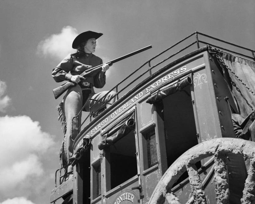 西方人,成年人,一个人,牛仔,舞台,栏杆,横图,黑白,室外,白天,侧面,仰视,窗户,帽子,欧洲,美国,欧洲人,仅一个年轻女性,仅一个女性,仅一个人,对抗,冲突,轮子,枪支,文字,云,马车,古典,注视,休闲装,车,两个,天空,车轮,交通工具,平原,观察,看,牛仔帽,猎枪,武器,斜视,角度,摄影,井,观看,英文字母,保护,察看,北美,北美洲,暴力,鄙视,关注,载具,美洲,防守,生存,美国文化,机敏,皮套裤,藐视,讽刺,蔑视,嘲笑,北亚美利加洲,亚美利加洲,法哥,机会,危险,年轻女性,女人,女性,白种人,美国人,年轻人,低角度拍摄,美利坚合众国,法律,韧性,篷车,富国银行集团