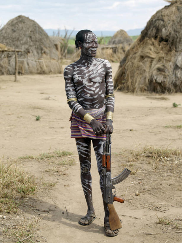 成年人,一个人,站,竖图,室外,白天,射击,埃塞俄比亚,仅一个男性,仅一个人,装饰,葫芦,枪支,房屋,仅一个年轻男性,白色,看,摄影,发辫,观看,住房,肖像,来福枪,AK47步枪,男人,男性,年轻男性,年轻人,彩图,传统服装,传统文化