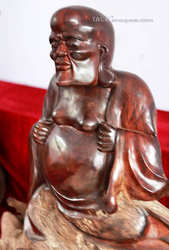 东方人,一个人,无人,和尚,坐,举,笑,微笑,竖图,室内,白天,正面,静物,雕塑,亚洲,仅一个男性,仅一个人,仅一个中年男性,阴影,节日,艺术,装饰,光线,光泽,木制,雕刻,雕像,佛像,影子,墙,棕色,织物,光芒,黄种人,文化,墙壁,墙面,红色,白色,阳光,木制品,工艺品,祈祷,托,健康,展示,许愿,宗教,根雕,佛教,信仰,纪念,展览,支撑,祈求,美术,主题,陈列,罗汉,功能,美学,释教,阿罗汉,开心罗汉,十八罗汉,戍博迦,戍博迦尊者,绒布,平安,男人,男性,中年男性,亚洲人,比丘,高僧,僧,僧侣,僧人,沙弥,修行僧,举起,举手,举着,向上举,向上伸,向上托,坐着,半身,彩图,rzwdb1