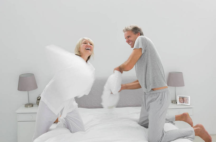 西方人,中年人,两个人,家庭,夫妻,跪,闭眼,笑,微笑,露齿笑,横图,室内,白天,侧面,爱情,游戏,床,柜子,靠垫,台灯,卧室,照明,欧洲,欧洲人,握,睡衣,服装,墙,双人床,灯光,床单,靠枕,浪漫,拿,玩,拿着,娱乐,被子,墙壁,墙面,灯,衣服,灰色,床头柜,灯具,垫子,枕头,休闲,温暖,温馨,一家人,恩爱,解压,握着,恋人,服饰,活动,照亮,和睦,被单,衣着,照明设备,储存,穿着,发泄,消遣,智力,家居服,缓解,宣泄,寝衣,衣饰,储备,蕴藏,贮备,男人,男性,女人,女性,中年男性,中年女性,白种人,夫妇,情侣,闭眼睛,闭着眼,闭着眼睛,跪着,玩耍,嬉戏,半身,彩图,睡房,卧房,枕头大战,伴侣,融洽,贮存