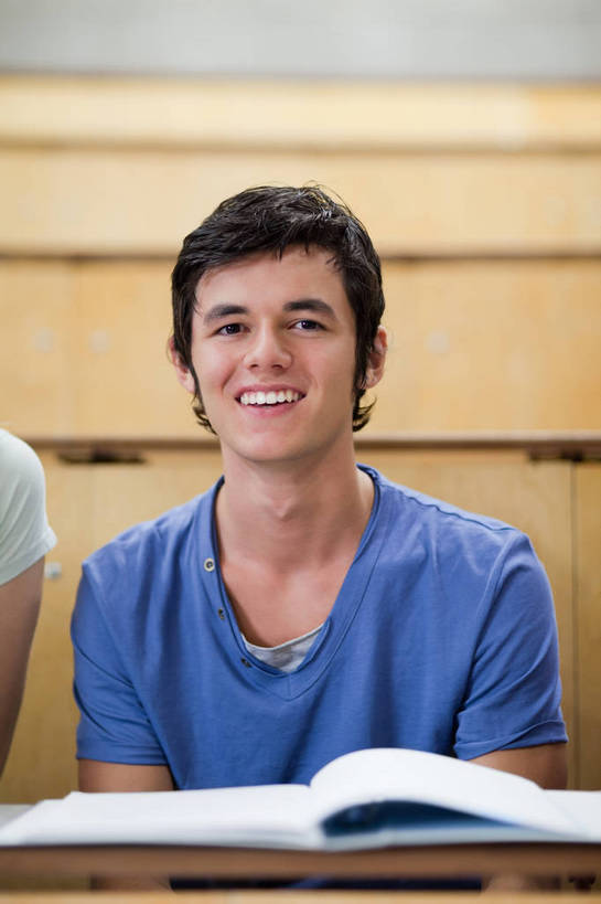 西方人,一个人,学校,坐,笑,微笑,露齿笑,竖图,室内,白天,正面,T恤衫,书籍,欧洲,欧洲人,仅一个男性,仅一个人,一本,阴影,服装,朦胧,模糊,反射,影子,墙,T恤,注视,休闲装,校园,墙壁,墙面,仅一个年轻男性,衣服,蓝色,书本,观察,看,休闲,教室,休闲服,服饰,观看,察看,课堂,阶梯教室,关注,男人,男性,年轻男性,白种人,书,图书,坐着,半身,彩图